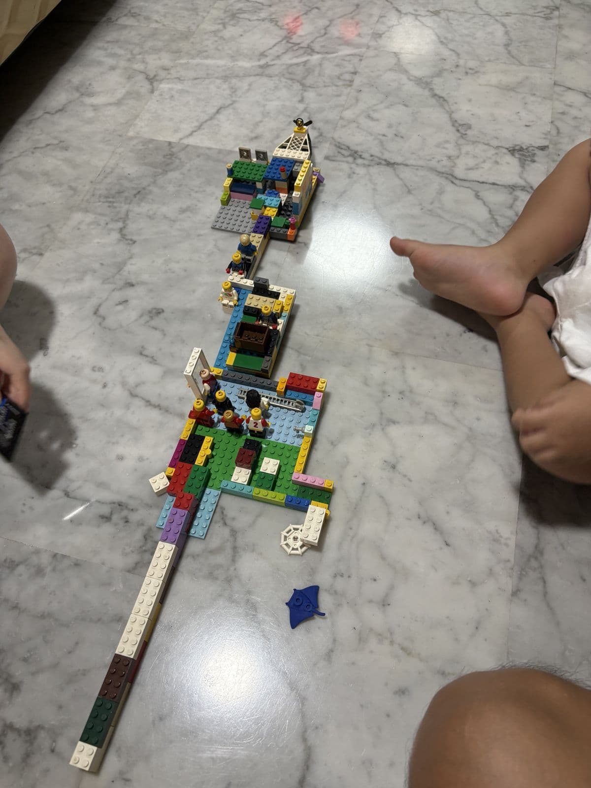 A long chain of Lego blocks and minifigure scenes stretched across a marble floor